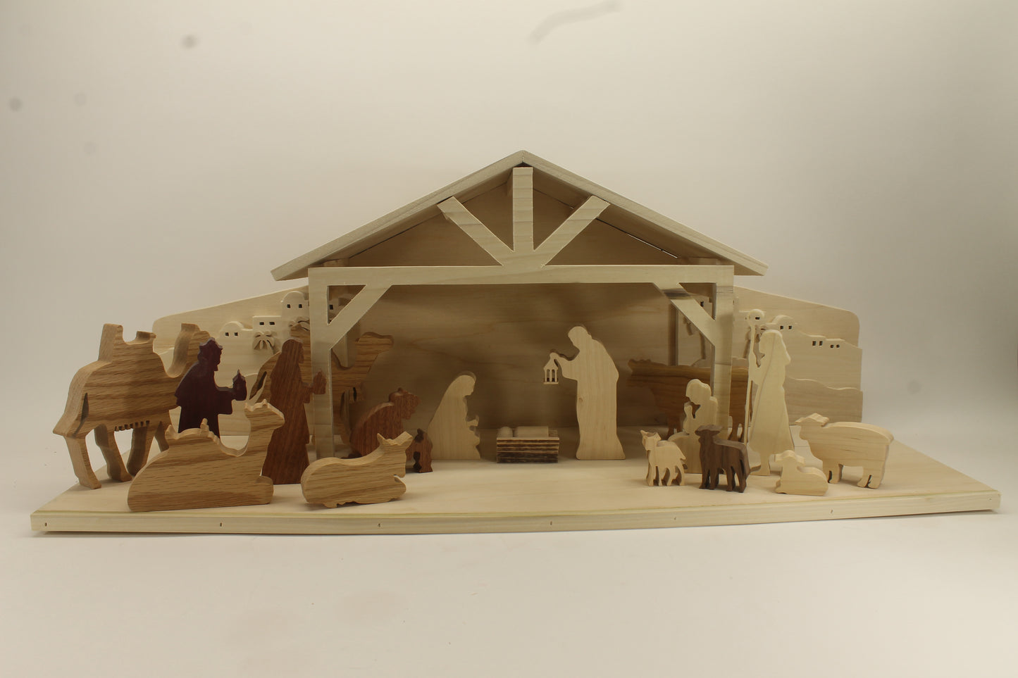 Multi-piece wood nativity with stable and figures, town of Bethlehem in the background