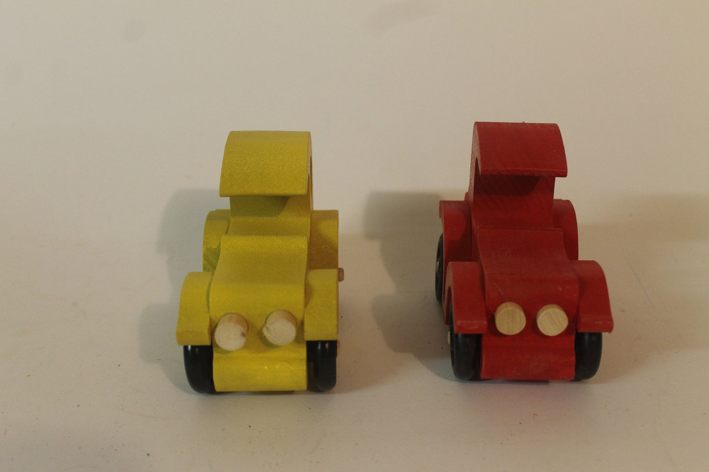 Two antique autos vehicle set. They are hand cut from solid poplar, have old type spoked wheels, and are painted bright red and yellow