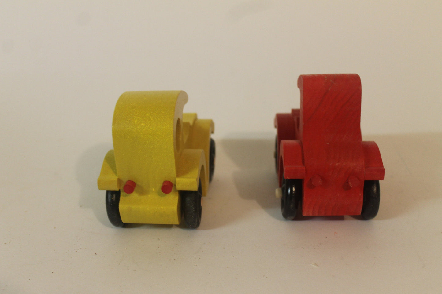 Two antique autos vehicle set. They are hand cut from solid poplar, have old type spoked wheels, and are painted bright red and yellow