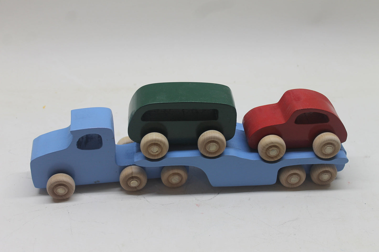 Volkswagen car carrier solid wood toy. Set includes a tractor with separate trailer, a VW bug, convertible, and van, and two people
